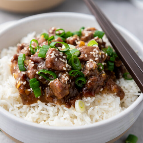 slow cooker Mongolian beef on top of a bowl of rice.