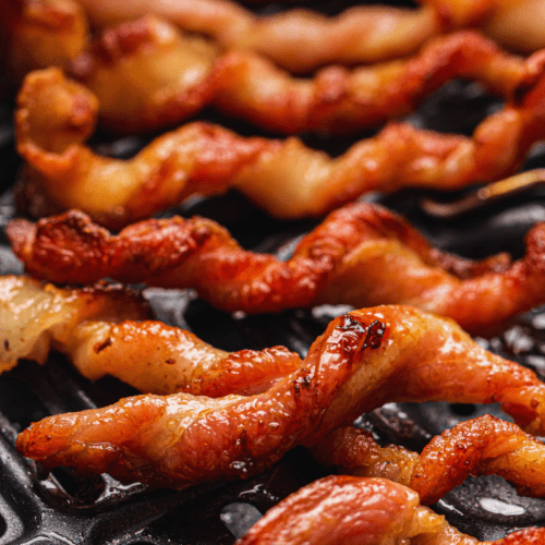 Close-up of twisted bacon strips in an air fryer.