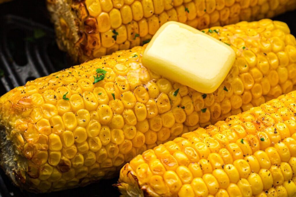 Close-up of grilled corn on the cob topped with a melting pat of butter.